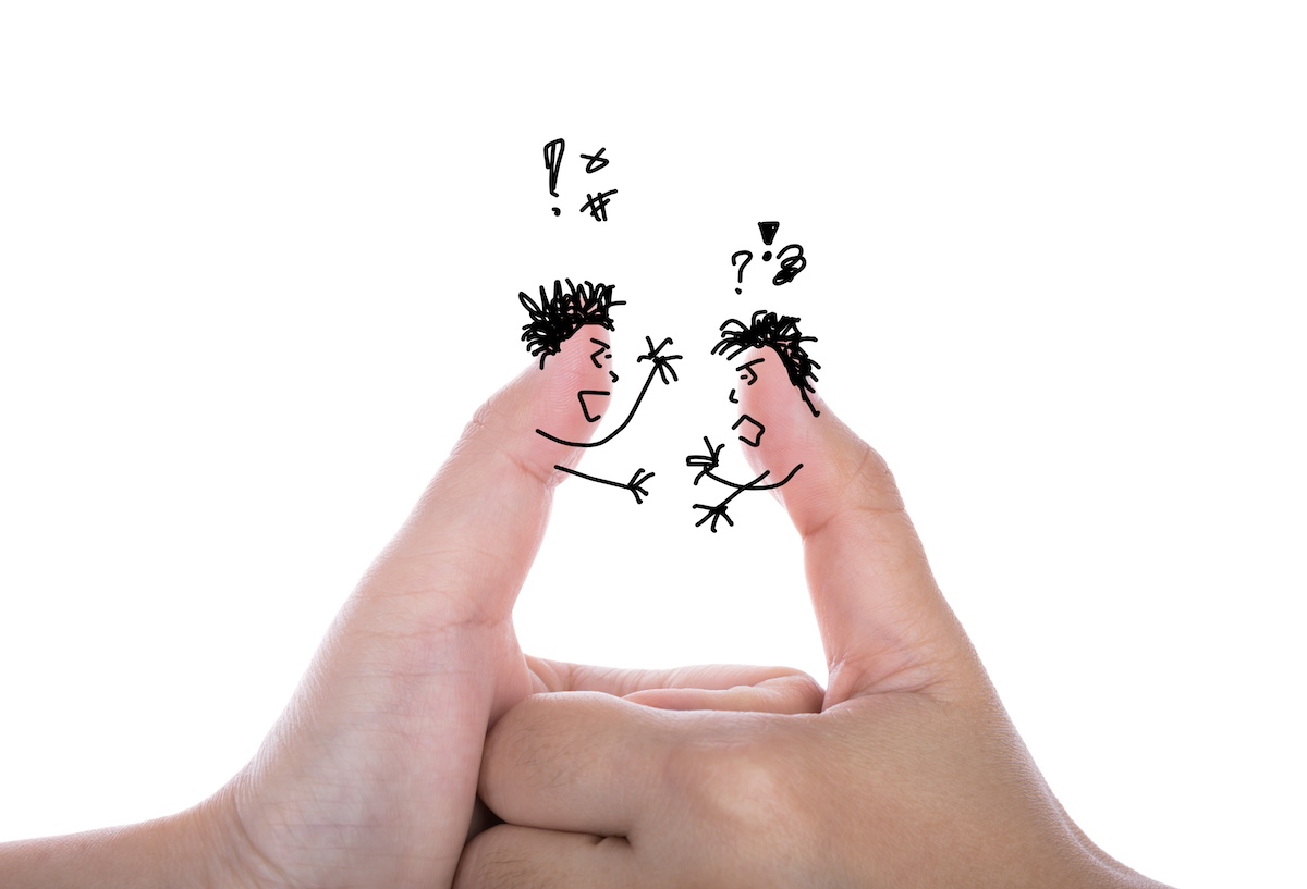 Dos polzes de dues mans on damunt s'han sibuixat amb boli expressions d'ambdós d'enuig, com si hi hagués un conflicte entre els dos