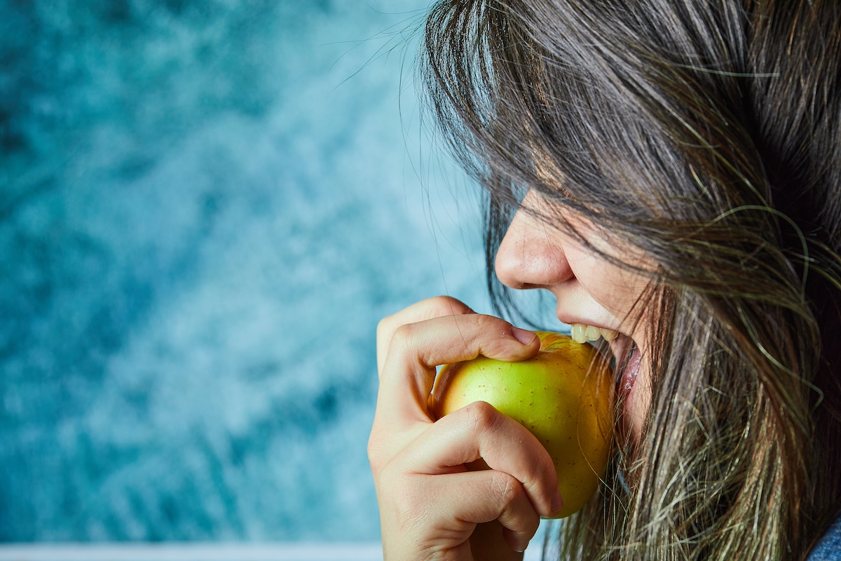 Una jove menjant una poma com a hàbit saludable enfront el consum de drogues