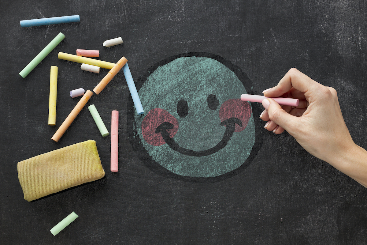 Dibuix d'una cara en un pissara de guix que expressa una emoció positiva o de contenta