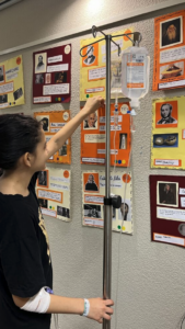 Alumne de les aules hospitalaries penjant els treballs de la exposició