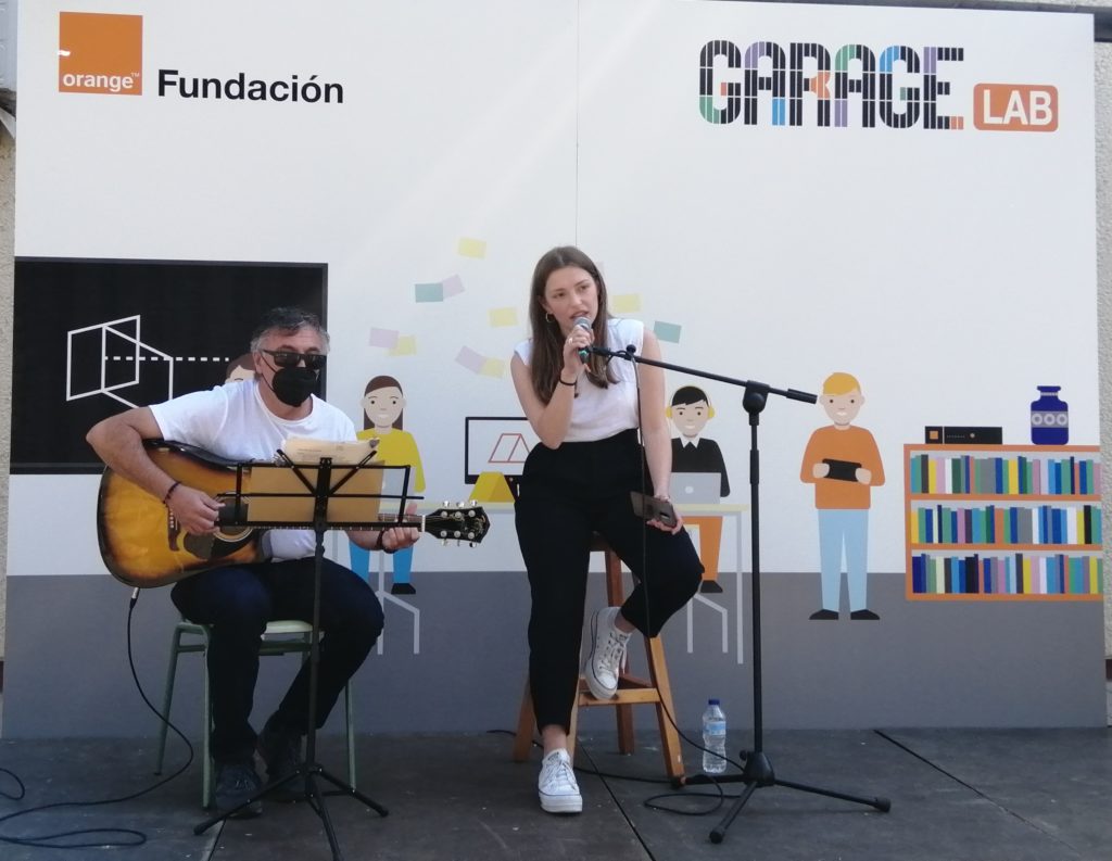 fotografia d'un noi tocant la guitarra i una noia cantant en la inaguració del projecte Garage Lab
